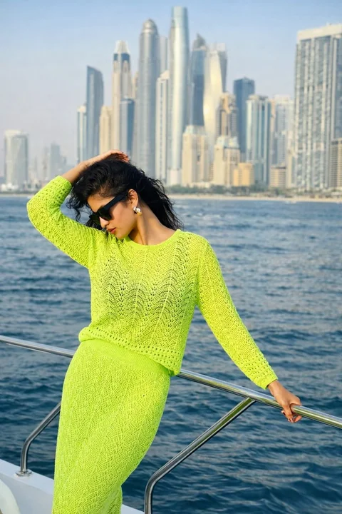 المرأة ذات اللون الأخضر اللامع على اليخت في البحر الأزرق