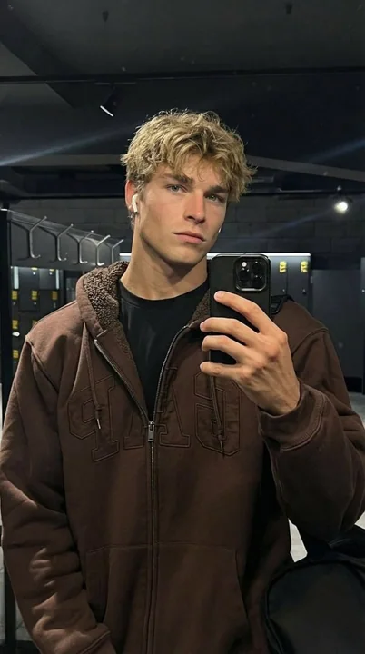 Homme aux cheveux dorés froid devant le miroir de la salle de sport