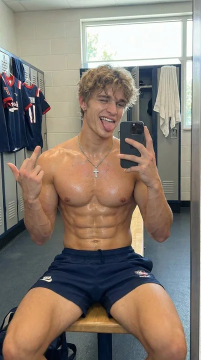 Homme musclé prenant une photo de lui-même devant un miroir dans les vestiaires de la salle de sport