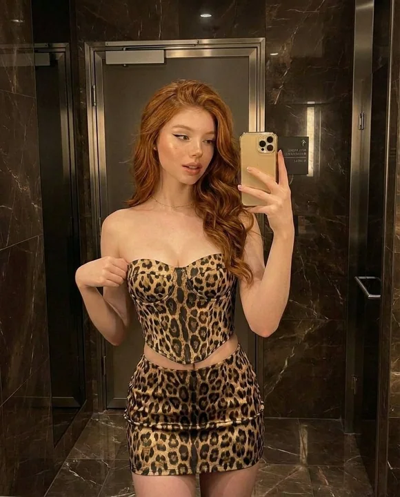 暖色光のバスルームで、赤毛の女性が豹柄の服を着てセルフィー