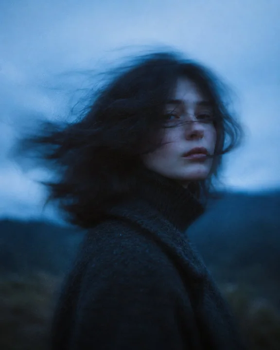 Portrait cinématographique d’une femme aux longs cheveux soufflés par le vent dans le crépuscule