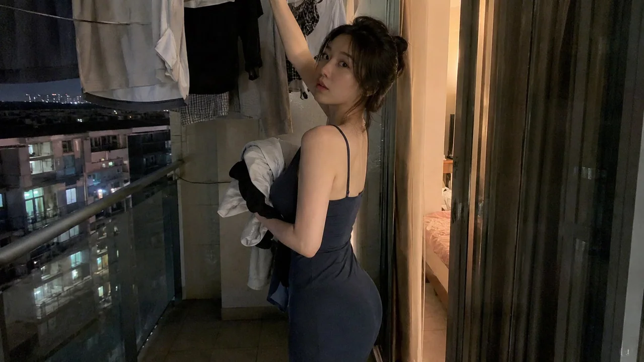 夜色阳台收衣服的真实感东方女性