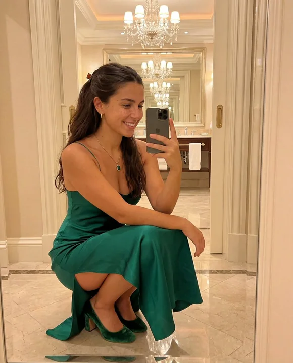 豪華ホテルでグリーンのロングドレスを着たエレガントなミラーでのセルフィー