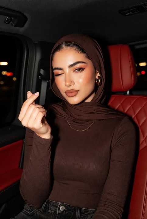 Movie-style photo of a beautiful woman in a headscarf making a heart gesture and winking inside a luxury car