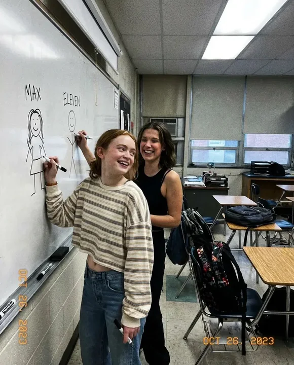 Blurred phone live stream of Sadi and Milly laughing and doodling in the classroom