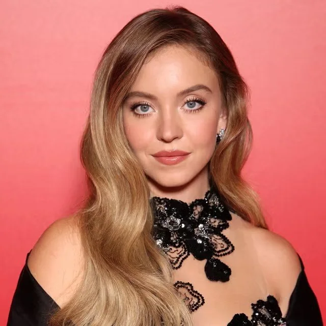 コーラルピンクの壁に映える、レッドカーペットの黒レース姿の女優