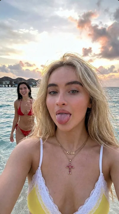 Jeune femme blonde sur la plage des Maldives prenant une photo coquine avec Dua Lipa