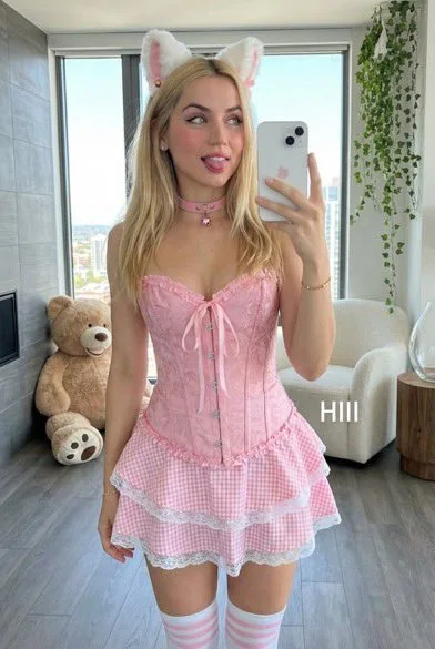 Jeune fille blonde aux oreilles de chat prenant un selfie espiègle devant le miroir, dans des tons roses, en tirant la langue