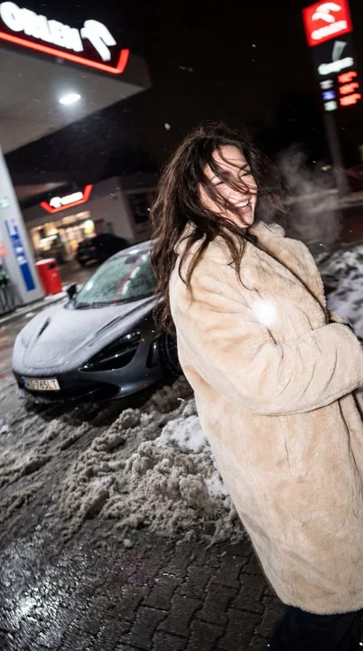 冬の夜、マクラーレンのそばでほろ酔いの毛皮をまとった少女